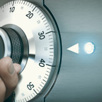Close up of a hand unlocking a safe deposit box by turning a knob with numbers. Composite image between a hand photography and a 3D background.