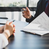 What does Bendel mean for SMSFs? Businessman in suit in his office showing an insurance policy and pointing with a pen where the policyholder must to sign. Insurance agent presentation and consulting insurance detail to customer.