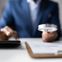 Business Fraud Investigation. Auditor Using Magnifying Glass To Investigate